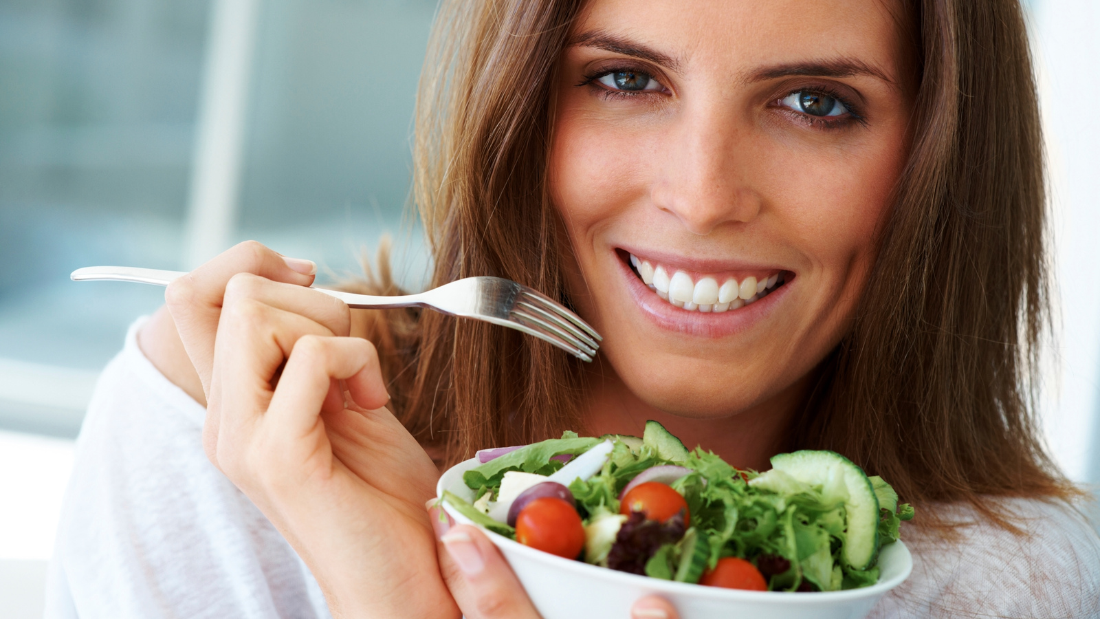 Close-up of happy woman eating vegetable salad