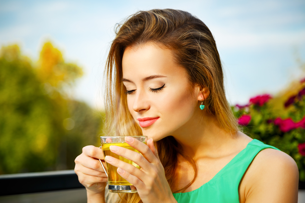 Young Woman Drinking Green Tea Outdoors. Summer Background. Shallow Depth of Field.